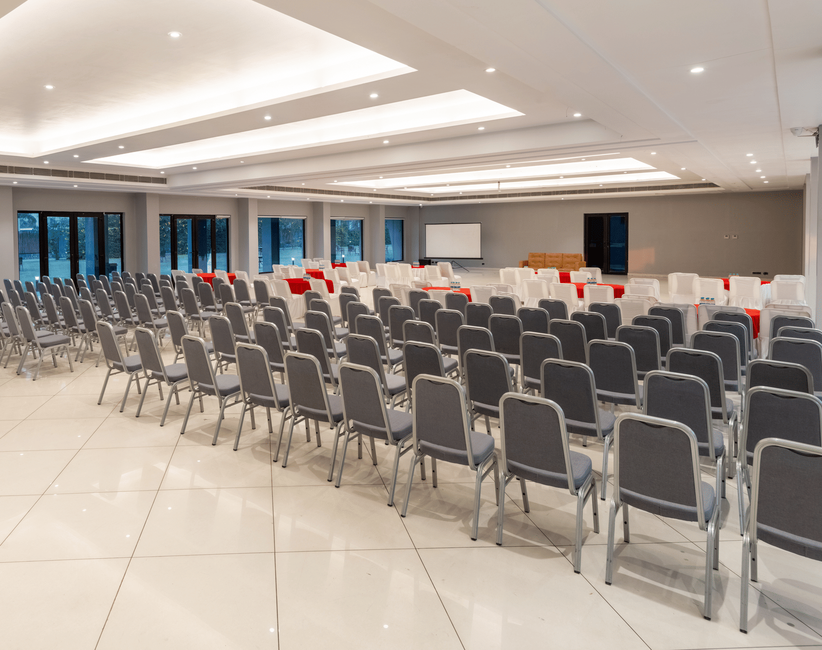 Spacious banquet hall at DLS Forest Vines Resort, with chairs neatly arranged and bright lighting illuminating the space.